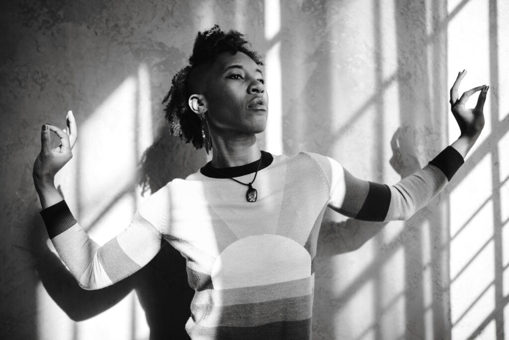 Black and white portrait of a stylish woman in geometric sweater with sunlight casting shadows.